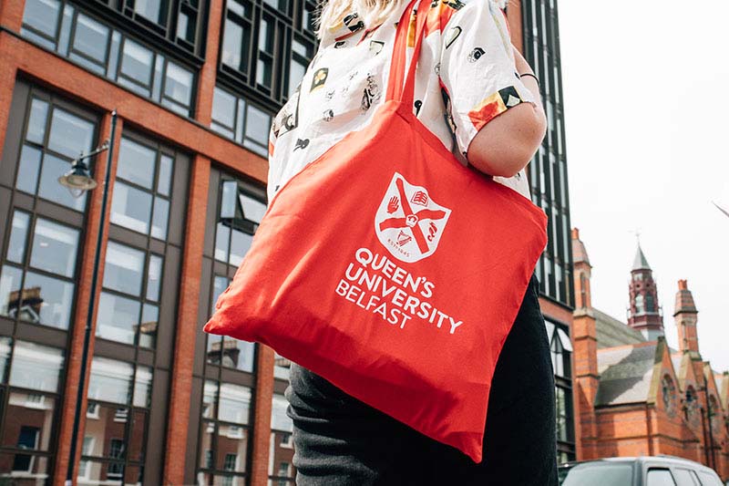 Student carrying a red University branded bag